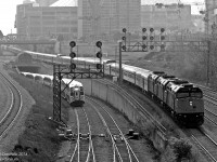 <b>MONSTER CANADIAN</b> <br><br> A mega monster of a 30-car summer Canadian consist threads its ways to Toronto's Union Station at Bathurst Street bridge, dwarfing the little 10 car GO trains puttering in and out of the corridor on a sunny morning just after 8am. <br><br> Today's consist featured 30 matching stainless steel Budd passenger cars including 5 domes, 7 Chateau sleepers, 12 Manor sleepers, 3 diners, 2 coaches and a baggage. 4 GMD F40PH-2 locomotives (3 on the head end, one on the rear) provided the power on this long train, whose rear end stretches all the way to Peter St. by the Skydome/Rogers Centre. <br><br> The train was so big they had to split it in two at Union Station to load it on two separate platforms, thus necessitating the F40 on the tail end to keep the other half of the train supplied with power when it was split. <br><br> After boarding and coupling both sections back together, the Canadian departed for Vancouver half an hour late, zipping past Bathurst St. again at 9:30am in a cloud of white 2-cycle EMD smoke. <br><br> <b><i>More at Bathurst Street:</i></b><br> The first rebuilt F40 on its maiden voyage west: <b><a href=http://www.railpictures.ca/?attachment_id=4210>http://www.railpictures.ca/?attachment_id=4210</a></b> <br> New and Old GO power morning mingling: <b><a href=http://www.railpictures.ca/?attachment_id=11141>http://www.railpictures.ca/?attachment_id=11141</a></b><br> GO and VIA train mania after rush-hour: <b><a href=http://www.railpictures.ca/?attachment_id=11000>http://www.railpictures.ca/?attachment_id=11000</a></b>