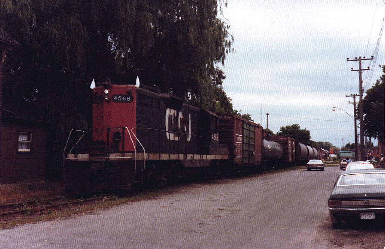 CN 4568 won't be going anywhere for a while. The rear end of the tank car and front of the second box car are on the ground on top of the switch to the CP interchange tracks. The signal protecting the diamond crossing is just visible to the right of the train. The train is on Bethune Street just south of Dalhousie Street. Behind the train was a vacant lot where a former turntable pit outlined in timbers was still visible. It's now a parking lot. There is a building still standing on Wolfe Street that has an angled wall from the former lead to the turntable. Photo by my brother with some editing assistance. I'm the kid cluttering up the photo under the street light.