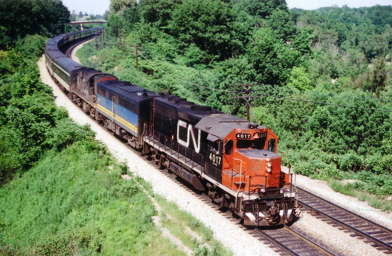 Here is another one of those old pre-VIA passenger train scenes, featuring the usual mish-mash of whatever power for the head end. CN 4017, VIA 6865, CN 3126 lead westbound #75, the days' usually most patronized train thru here, with the standard long consist. I always referred to this location as 'Bayview East' on account the train is approaching Bayview Jct. Nowadays the location is known as "Snake", and it is getting increasingly difficult to get clear photos here due to new signal tower and encroaching foliage. The leader, GP40 CN 4017, was renumbered to 9317 in 1981, and may still be around somewhere as GMTX 2103. Trailing unit RS-18 was part of a series 3100-3129 committed to passenger service back in those days. Snake Rd bridge in the background is still used by fans for photography, but it is imperative that the bridge and approaches be kept clear despite the lane being a dead-end. Private access to a cemetery.