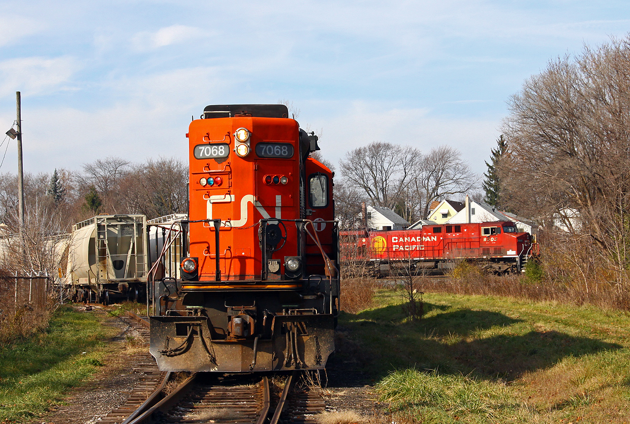 To follow Stephen Host's photo of CP and Amtrak at Bayview, here is the most recent time I caught two different railroads in the same shot. Many photographers know about the Denfield road bridge at Lobo, but there is another place to catch CN and CP together in London. A Sunday CN Racecourse job has run up to the CN/CP interchange to set off one boxcar and lift a number of MT cement cars to bring back to the yard. In the back ground, CP 240 has just got his clearance and is heading out of town.