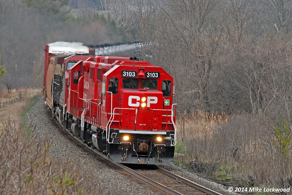 CP 3103 and 3027 lead 8642, T25's train and then 609's train at Port-Hope (you can see the mileboard through the trees above 3103). Not sure of the exact story here, but this is a rescue and, given the GP38's are leading and that the GE is on line, appears as though 609's crew ran short on hours somewhere east. 1424hrs.
