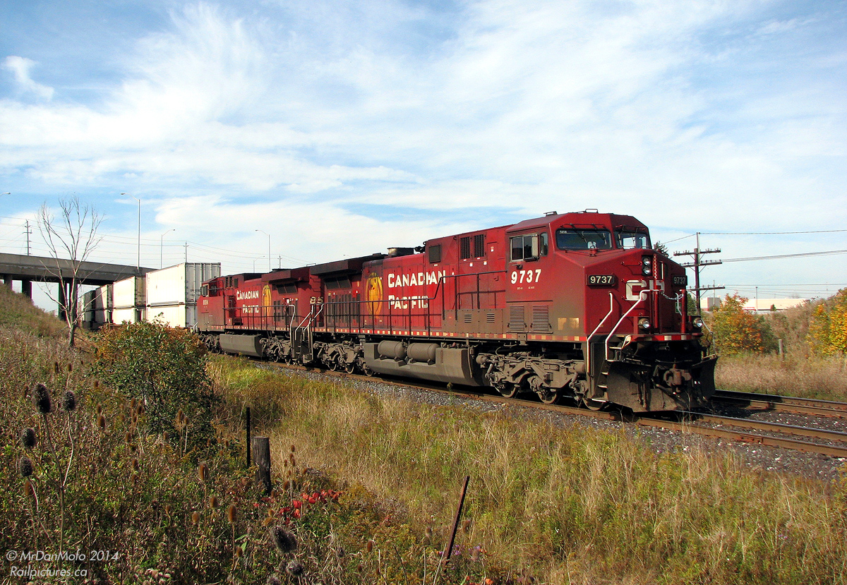 CP 104 with a pair of golden rodent-bearing GE AC4400CW's on the head end, CP 9737 & 8554, sits at the south siding switch at Bolton ("Begin/end CTC sign Bolton, B-O-L"), awaiting the light to head south to CP's Vaughan Intermodal Terminal to deliver their train of cross-country intermodal containers (and then subsequently head to Toronto Yard light power). Highway 50 / Queen Street sits in the background on a sunny afternoon.