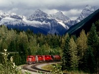 Westbound just west of Rogers Pass. We were driving west, not far ahead of the train, when we saw this kind of lighting in the rear view mirror. We quickly pulled off the road, jumped out of the car, and looked for a shot. Unfortunately there were a bunch of bushes in the way. But by standing on the tip of my toes I could barely shoot over the bushes.
