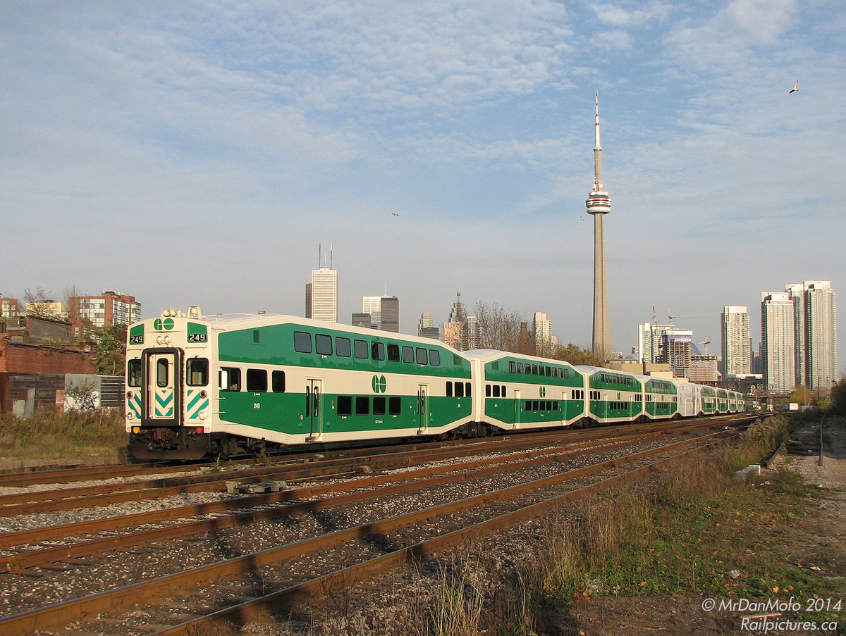 The sun is already starting to set as GO train 207 leaves downtown Toronto behind, about to cross Strachan Avenue to head up the CN Weston Sub with a fully loaded (read standing room only) 10 car consist of Bilevels. Nearly new cab car 249 is rocking back and forth over the crossovers, e-bell ringing and ditch lights flashing, with F59 553 pushing lightly on the tail end, maintaining the 30mph speed restriction for the crossing before opening it up to 55.This area of Toronto is King St. West and Liberty Village, divided by the rail corridor that once serviced the many factories and industries on both sides. Condos, townhouses and loft conversions are the order of the day. To accommodate increased GO service and increased neighbourhood traffic due to development, this entire area of the corridor was lowered and the crossing eliminated in a flyunder underneath Strachan, nixing this convenient photo spot.