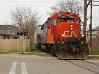 CN 4721 leads a single hopper down the Burford Spur, they are seen here crossing Cayuga Street on their way to Ingenia.