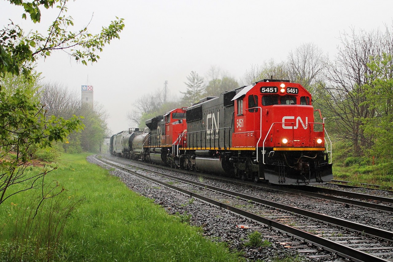 Having to take my wife and daughter to Woodstock for the Windsor train I managed to get there an hour early just as a thunderstorm hit!! I heard on the scanner that a train was on it's way. I rushed to the bridge at the west end of the station to keep my camera dry just as the train arrived . CN5451 &CN8001 were heading east with a train of coil cars and tankers. A short train speeding through the station. By the time I got back to the car I was soaked!