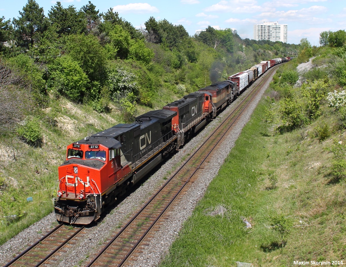 On a very hot and sunny day in May, a westbound Canadian National train with a one of a kind lash-up goes by Hilda. At the last position, is CCGX 1004 showing CANDO on the side in black paint, which is a yard switcher. Any info on that would be appreciated.