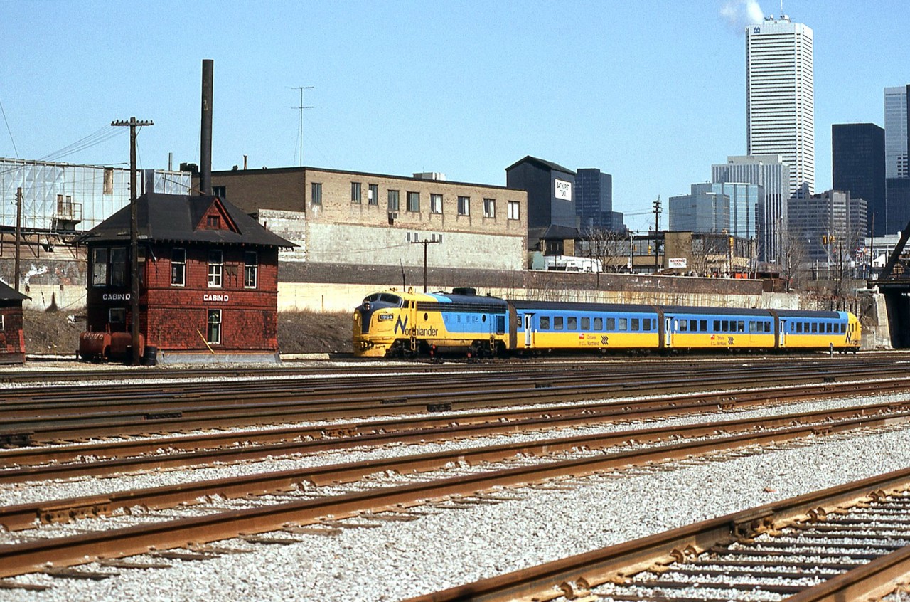 Ontario Northland's Northlander, made up of an FP7-TEE trainset, has departed Union Station in the downtown core of Toronto, enroute to northern Ontario on this Sunday departure back in March of 1984. At Bathurst Street brige about to leave the Toronto Terminals Railway corridor, the train is passing the old Cabin D interlocking tower, heading to the CN's Weston Sub to get to the Newmarket Sub at Parkdale.

While the Northlander's final run was in September of 2012, and the FP7's and TEE equipment is long retired, Cabin D survives and currently rests at the nearby Toronto Railway Heritage Association's Roundhouse Park in restored condition, according to their website it was moved there later in 1984.