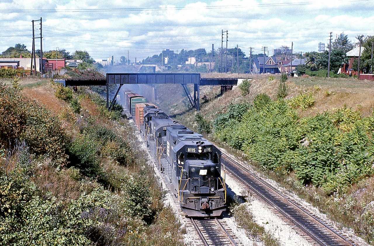 With recent photos on Railpictures.ca of trains around the Detroit River Tunnel, here's an oldie from the same spot to compare with: a Penn Central freight pops out of the tunnel arriving on the Canadian side in Windsor, with a cloud of white exhaust. Power is PC GP38-2 8115, U25B 25xx (likely a former NYC U-boat), and GP38 7863, all in the black PC scheme with "mating worms" logos.