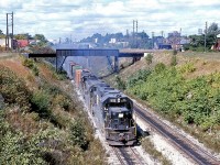 With recent photos on Railpictures.ca of trains around the Detroit River Tunnel, here's an oldie from the same spot to compare with: a Penn Central freight pops out of the tunnel arriving on the Canadian side in Windsor, with a cloud of white exhaust. Power is PC GP38-2 8115, U25B 25xx (likely a former NYC U-boat), and GP38 7863, all in the black PC scheme with "mating worms" logos.