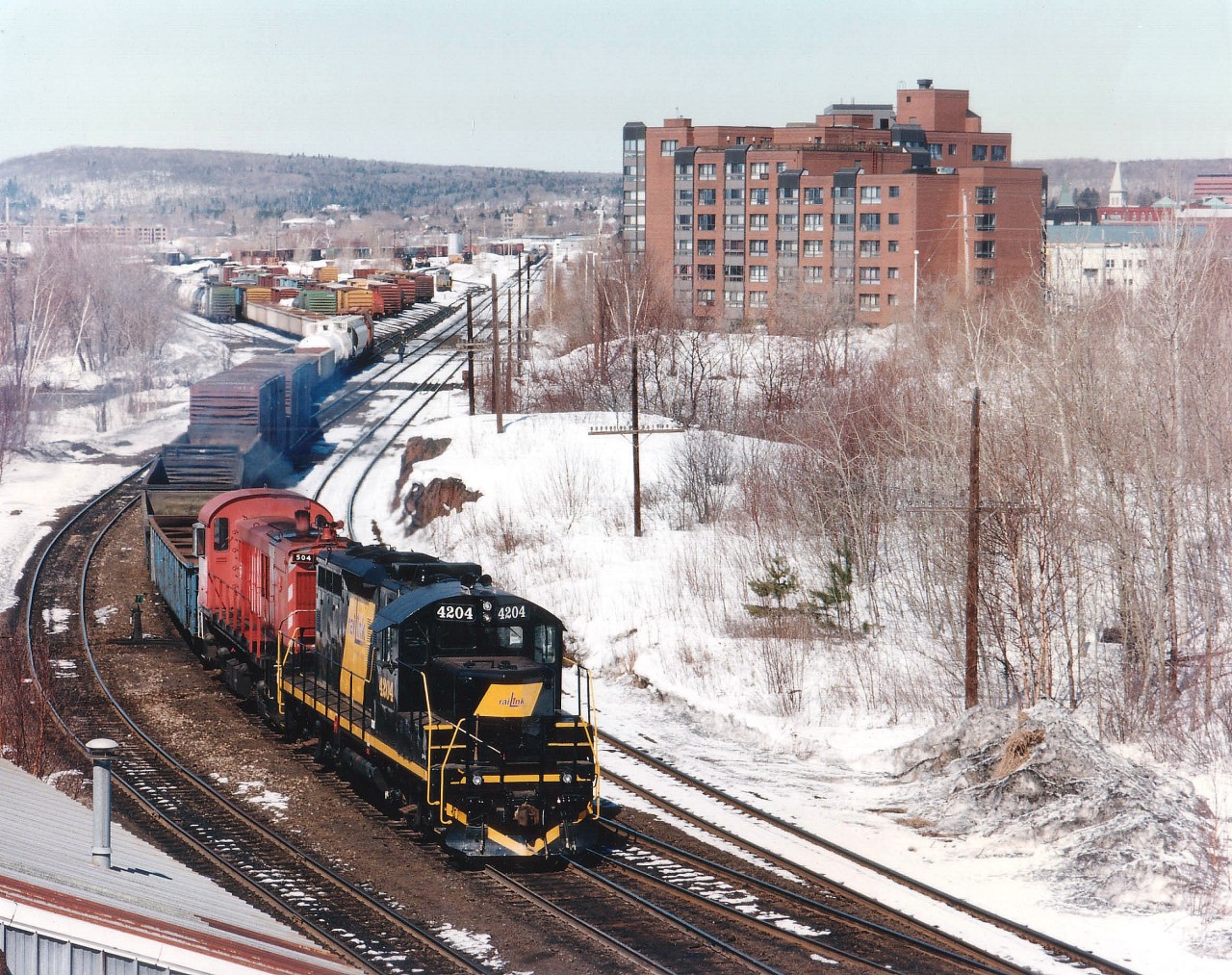 View from Main St. overpass looking NW toward the former Ottawa Valley(CP) yard that has now been moved south of the city in order to free up valuable waterfront/downtown lands. OVR 4204 and OSRX 504 are seen working a long cut of cars. The 4204 was acquired in 1996 and shortly after this photo was taken departed for Lakeland and Waterways startup in Alberta that September. It has since been retired. The second unit, former CP 8044, renumbered 504 assigned Guelph Jct Rwy, was on loan. It today still smokes-up on the GJR.