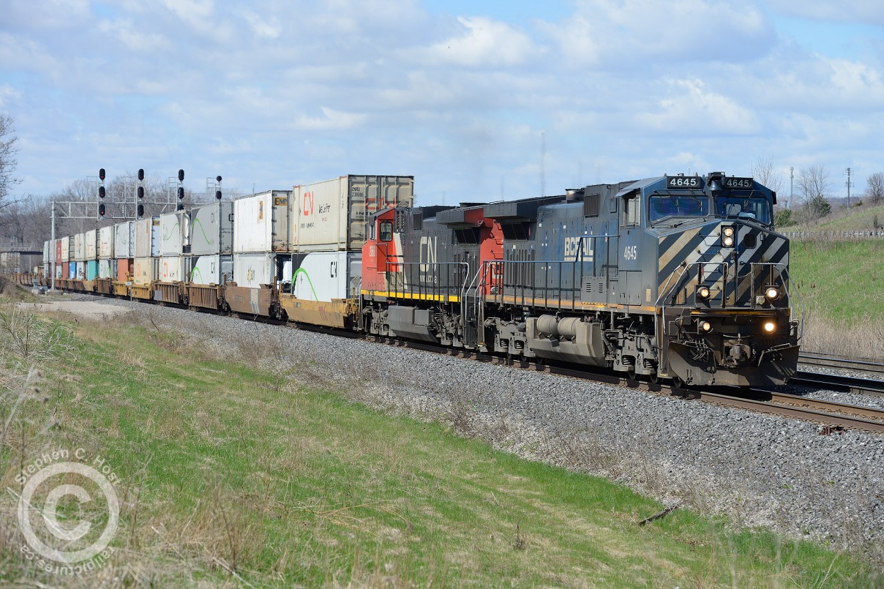 BCOL 4645 has the honours on the hottest frieght on the CN Chicago to Toronto mainline - CN M148 passing the cars on the Highway 403 at far right.