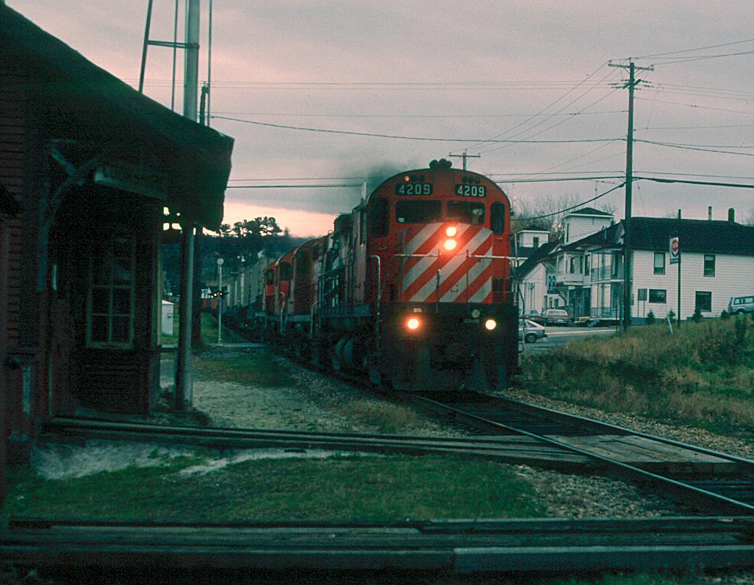 Extra 4209 East hammers through Cookshire, Quebec on a typical dreary day in the eastern townships in April of 1986.