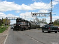 <b>Jigsaw Puzzle Switching</b>. Playing with traffic on Broadway Avenue, the Orangeville-Brampton Railway's sole 50-year old GP9 (CCGX 1000) works the industries at the north end of Orangeville, after making the interchange run to Streetsville and back. The north end switching is a bit of a game in itself, and can interfere with traffic multiple times while the train constantly shuffles cars around...<br><br>See if you can follow along:<br><br>Today, they left Orangeville Yard with three cars (2 tanks and one hopper) for the two north end customers. Switching Symplastics and PolyOne, the former of spots its cars directly on the industrial spur, and requires moving their cars first to service the latter. The first three hoppers here were Symplastics cars that had to be moved in order to access PolyOne further in. The 4th hopper at the back (the one they left with) will then be spotted at PolyOne. The train will then lift the two outbound tanks from PolyOne and set them off back on the main, along with one of Symplastic's hoppers. Then they'll spot these inbound PolyOne tanks, respot the remaining Symplastic cars on the spur, lock the switch and head back down the main to the yard to tie down, with a Symplastics hopper and two PolyOne tanks.