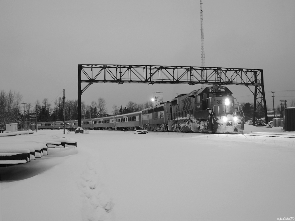 ON 1805 South stopped for a quick pickup with train "six ninety late" in Washago under the old signal tower that used to govern the 4 tracks previously running through town. Coming towards you from the far side you had the Newmarket main and the Newmarket siding, paralleled by the Bala main and the Bala siding. While only the Newmarket and Bala mains were used daily, it wasn't uncommon to see some work trains/through freights utilizing the Bala siding for leaving equipment/setting off bad order cars. 


Plenty has changed from those days, now only the Bala main runs under the old signal tower, which has now been torn down and forgotten by most. The terribly unreliable Northlander (pictured here over an hour late) is no more, and the last locomotive to dawn ONR's Chevron paint scheme from the road power pool is mothballed waiting for an engine rebuild and slated for repaint in North Bay. I remember standing on the platform here as a kid waiting for one of the 8 signal lights on this old tower to change to any color, only to be disappointed when the Northlander came around the corner with a boring old Chevron unit. The things we take for granted...