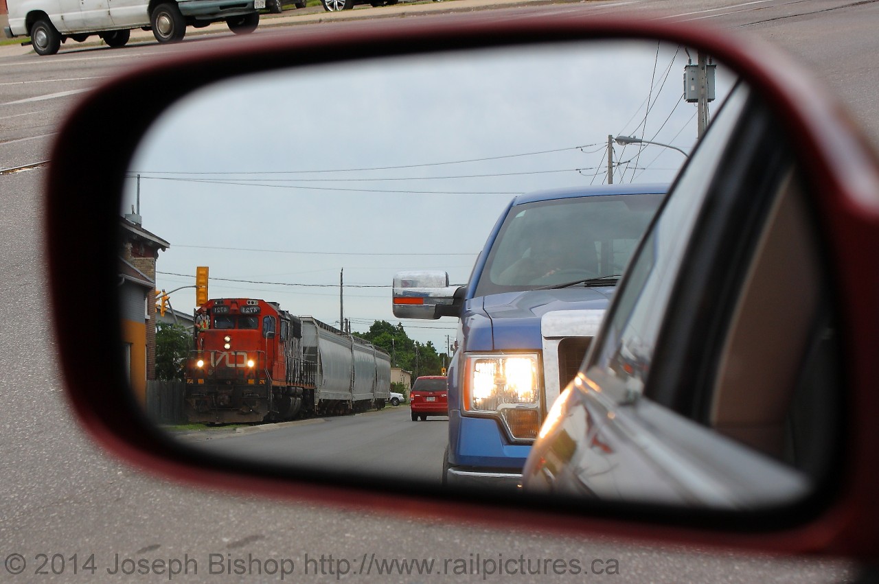 CN 580 slowly trundles down the Burford Spur along Clarence Street in downtown Brantford.  While driving down Clarence I was stopped at Dalhousie Street waiting for a green light and I noticed that I could see 580 entering into my rear view mirror.  I grabbed my camera and took a few shots before the light turned green and I had to carry on down the road.