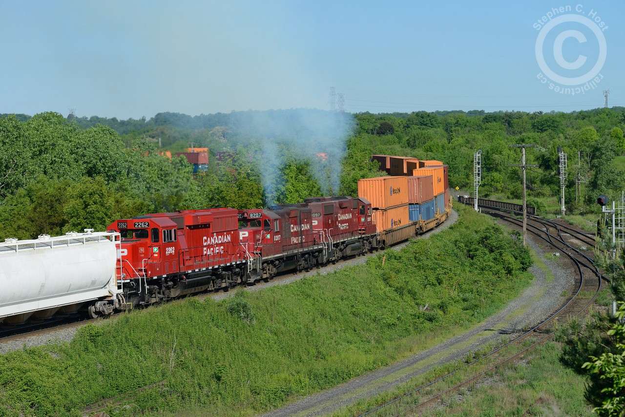 Give me all you got the head end of CP 142-06 says to the crew of "work CP 3097, TH11-07", attached at the rear of the intermodal train. Almost like planned clockwork, 142 and TH11 danced into the CTC at Desjardins, both receiving work clearances between Desjardins and begin/end sign CTC Guelph Junction, the pusher set given a protect against Work CP 6049, and off they go up the hill. The head end crew radios instructions to the tail end crew matching notches as the track profile warrants. Bang, Bang, Bang -  the slack has given out as the tail end reduces to idle -- predictably the train is quickly slowing. Head end says to tail end crew "we've passed the bridge, ok to apply throttle" and within 15 seconds similar bangs are heard as the slack bunches back in.  Train speed is barely increasing, and one last instruction over the radio is heard "give me all you got!".
In a few moments any chirping of the radio is no longer audible as three geeps giving all they got pass me in a puff of smoke as I snap a couple photos. The car at rear is for TH11 to set-off at Barnes near Waterdown, making for what at first glance looks like a real mid-train pusher set, but looks are deceiving :)