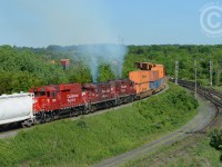 <b>Give me all you got</b> the head end of CP 142-06 says to the crew of "work CP 3097, TH11-07", attached at the rear of the intermodal train. Almost like planned clockwork, 142 and TH11 danced into the CTC at Desjardins, both receiving work clearances between Desjardins and begin/end sign CTC Guelph Junction, the pusher set given a protect against Work CP 6049, and off they go up the hill. The head end crew radios instructions to the tail end crew matching throttle as the track profile warrants. Bang, Bang, Bang -  the slack has given out as the tail end reduces to idle -- predictably the train is quickly slowing. Head end says to tail end crew "we've passed the bridge, ok to apply throttle" and within 15 seconds similar bangs are heard as the slack bunches back in.  Train speed is barely increasing, and one last instruction over the radio is heard "give me all you got!".<br>In a few moments any chirping of the radio is no longer audible as three geeps giving all they got pass me in a puff of smoke as I snap a couple photos. The car at rear is for TH11 to set-off at Barnes near Waterdown, making for what at first glance looks like a real mid-train pusher set, but looks are deceiving :)