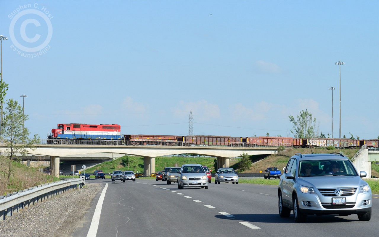 GEXR 582 is returning from Galt on the Fergus spur with dimensional load spacers (filled with ballast) and a dimensional load (out of sight) from Innovative Steam Technologies. Seen crossing the "Hanlon Expressway - Highway 6" in Guelph.