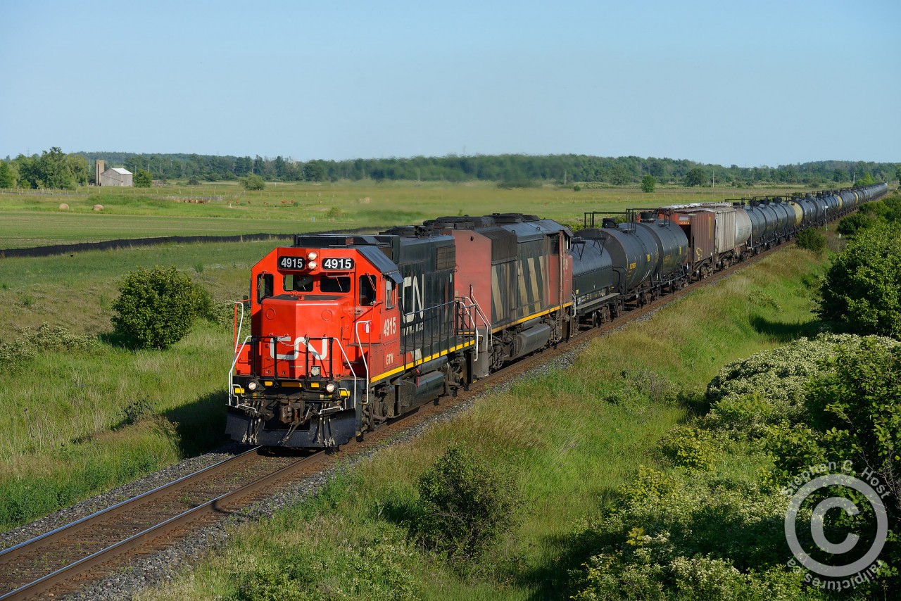 We're at the now-outskirts of Milton and I'm standing on a new road  and overpass risen from the earth - the fields at left, and right of me are slated to become cookie cutter housing. I'm sure there will be plenty of gas stations, boston pizzas, wild wings, and walmarts to go along with the beautiful escarpment and rapidly dissapearing farmland, oh boy I can't wait! Get your shots while you still can!
L570 is returning from Paris with a cut of cars after delivering empty autotracks for Beachville. GTW 4915 is in the lead due to no place to wye (Paris restricted to four axle and may be spiked).