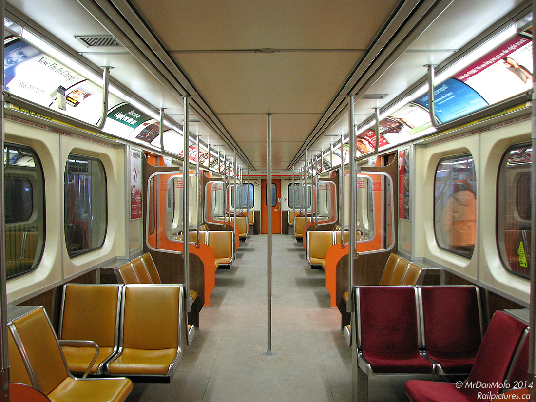 The original interior look of the TTC's UTDC-built H6 subway cars before they were all rebuilt: yellow vellor seats, bright orange doorways and simulated wood grain panelling - all straight outta the 80's. When rebuilt in the mid-2000's, the TTC had modernized most of these with darker orange doors and the red seats (as seen on the right). All were done by December 2008.This one, TTC 5891, briefly sits empty at the end of the line after discharging all of its westbound passengers, waiting to take on more at Kipling Subway Station before heading back east to Kennedy along the Bloor-Danforth subway line.