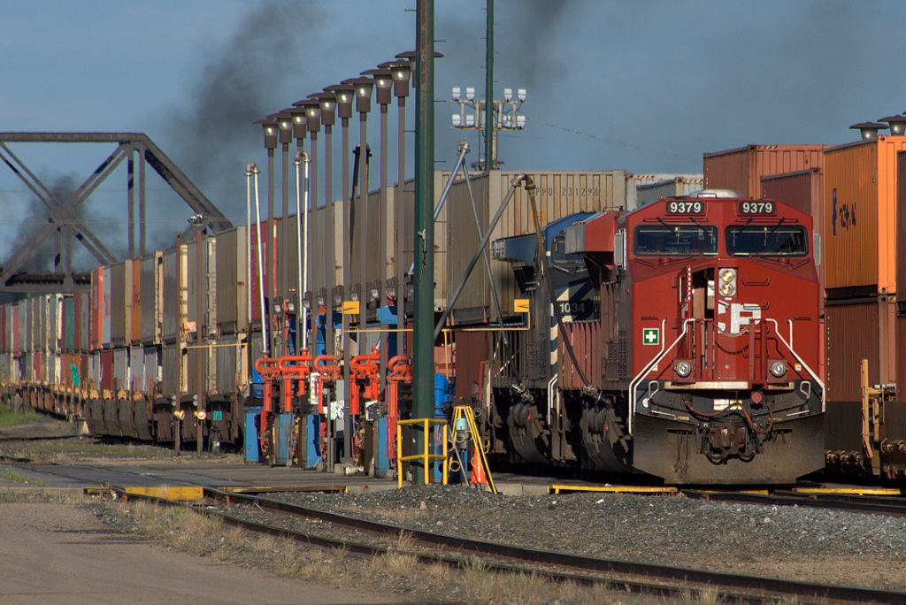 CP 9379 & CEFX 1034 Stop for some fuel and a new crew before heading west to Calgary. Plumes of smoke are the departing eastbound inter modal headed for the US.