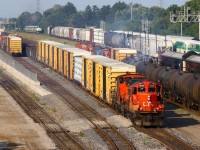 CN GP9RM 7075 and GMD-1 1412 wait to clear track 32 to the lower yard as 399 begins to back 22 autoracks for Ford onto track 30 (off screen to the right). The rest of 399 is sitting on main track one in the background beside the Hamilton bound GO train at the station on main track two. Way in the background the westbound L-10-L GO train leave Aldershot on main track three. Rush hour is a bus time for the dispatcher, which translates into entertainment for railfans!   