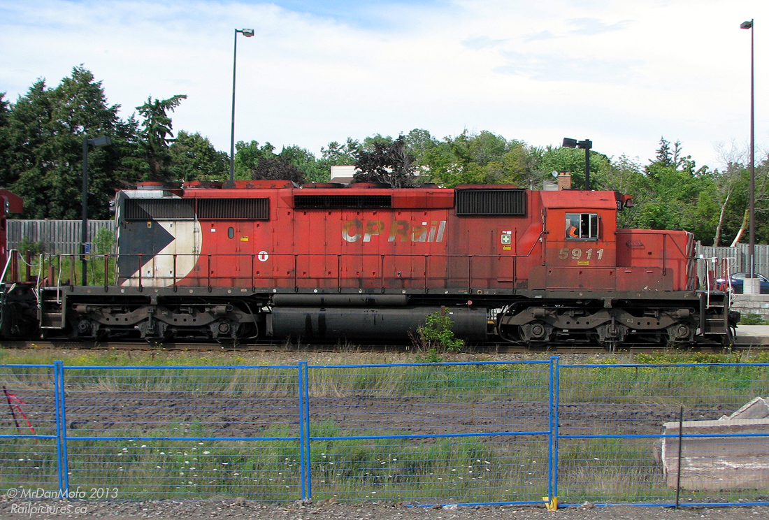 Seen better days. Built in 1979 at General Motors Diesel's London assembly plant, this is what a locomotive looks like after nearly 30 years of hard use. Still wearing her original paint and one of only two units sporting the full-height "Large Multimark" logo at the end, CP SD40-2 5911 hustles an eastbound freight through Streetsville on the way to Toronto Yard, while the photographer tries to dodge construction obstructions from the ongoing platform expansion project.

There's about 3 different shades of faded red on her, with a well-worn coat of dirt and road grime from all across North America built up over the years (regular washings and cleanings are a thing of the past). Oil from the 3000hp 16-645E diesel engine streaks out the bottom of her hood doors, down the frame and fuel tank. Tattered "CP Rail" lettering dating from about 3 corporate identity changes ago still clings to the hood doors, well-scorched by a hot exhaust manifold after countless miles of running full-throttle.

More subtle signs of hard use rivet counters will pick up on include 3 different styles of wheel roller bearings (after unknown many wheel, traction motor and truck changeouts), replacement fan bases still in grey primer, quickie safety white touch ups on the handrail ends, new and additional labels and warning stickers all over, and who knows what else under the hood.