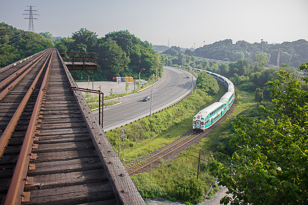 At the height of the rush hour commute, traffic stands still on the Don Valley Parkway in the background. Meanwhile, GO train 836 from Richmond Hill passes under the abandoned "Half-Mile bridge" of the CP Don Branch at Rosedale interlocking. Built it 1928, this bridge is no where near a half mile long, but is definitely enough to make someone look out in awe over the Don Valley, or panic. It was originally intended for freight and passenger service into the Union Station Rail Corridor. However, times changed of course, and the last train ran across this bridge in December 2007, which was the CP Holiday train. 

As you can clearly see, this is a risky shot. There is no railing on the side of the bridge, and the entire Don Branch is filled with thick, sharp and poisonous weeds. The line is completely abandoned, and it would be pretty much physically impossible for a train to access it, however I'd recommend not using it for the above reasons. It's definitely a hazardous trip, and I'm debating even doing it again.