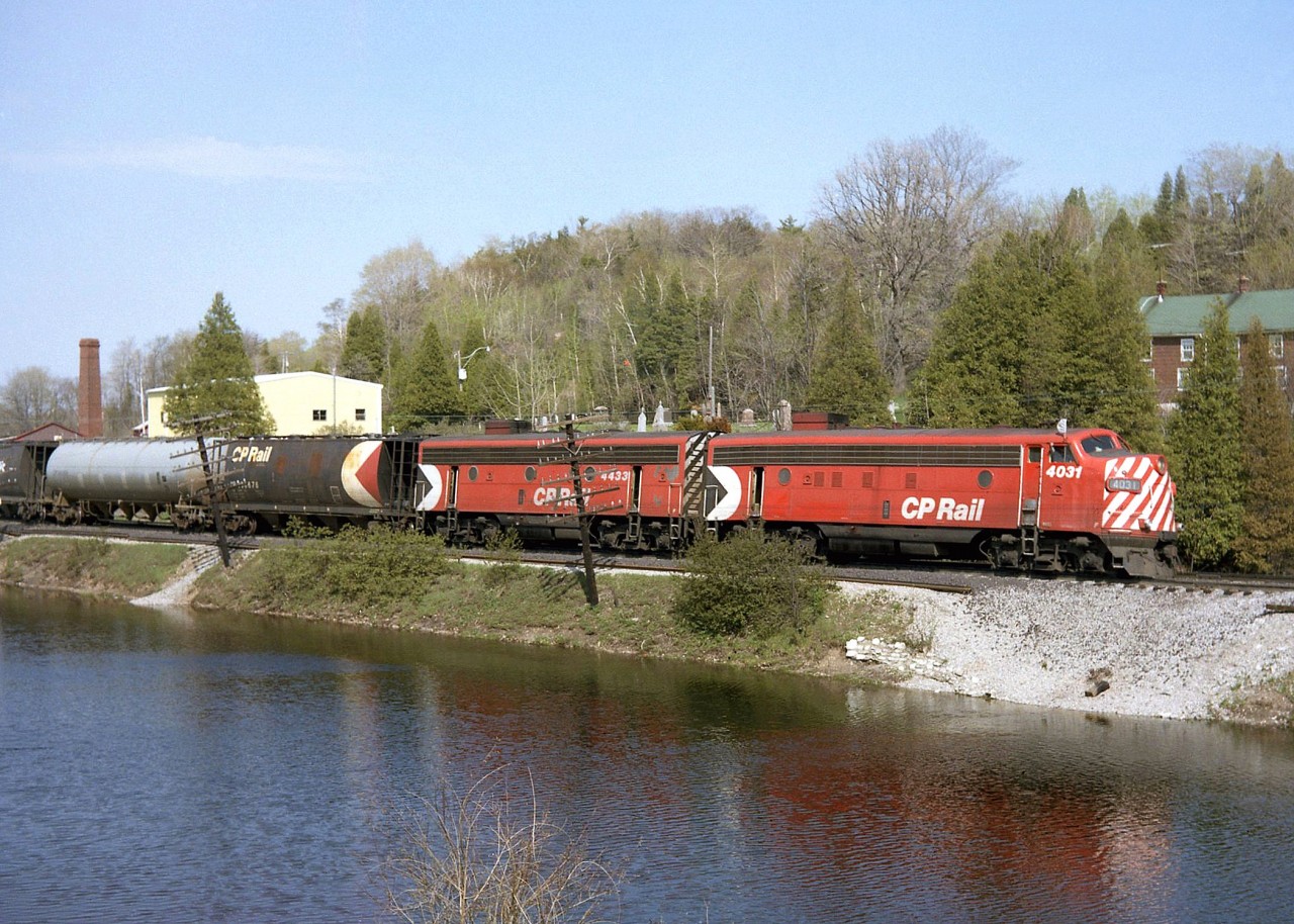 An A-B pair of matching F-units in CP's Action Red, FP7 4031 and F7B 4433, head west on the Galt Sub through Campbellville passing the ponds. Also of note are the early design cylindrical hoppers behind, bracketing a grey pressure-flow covered hopper. This scene is a difficult shot today due to the foliage growth.

The remaining GMD F-unit fleet on CP only had a few more years to go, before being retired en masse in 1982 (although a few remained in Montreal commuter service before going to CTCUM).