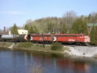 An A-B pair of matching F-units in CP's Action Red, FP7 4031 and F7B 4433, head west on the Galt Sub through Campbellville passing the ponds. Also of note are the early design cylindrical hoppers behind, bracketing a grey pressure-flow covered hopper. This scene is a difficult shot today due to the foliage growth.
<br><br>
The remaining GMD F-unit fleet on CP only had a few more years to go, before being retired en masse in 1982 (although a few remained in Montreal commuter service before going to CTCUM).