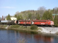 An A-B pair of matching F-units in CP's Action Red, FP7 4031 and F7B 4433, head west on the Galt Sub through Campbellville passing the ponds. Also of note are the early design cylindrical hoppers behind, bracketing a grey pressure-flow covered hopper. This scene is a difficult shot today due to the foliage growth.
<br><br>
The remaining GMD F-unit fleet on CP only had a few more years to go, before being retired en masse in 1982 (although a few remained in Montreal commuter service before going to CTCUM).