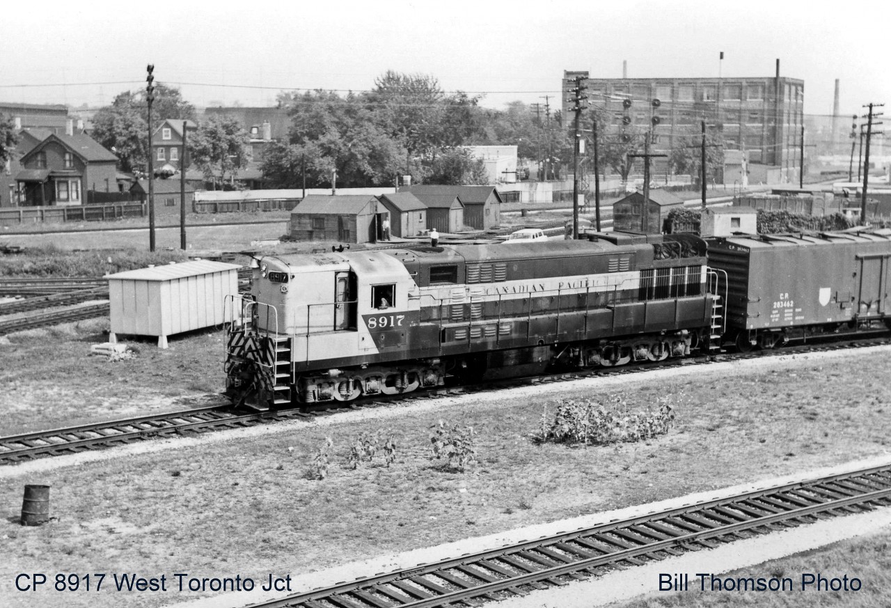 The scene at West Toronto diamond in 1965, looking east off the old Weston Road bridge that once crossed over the tracks here. Note the abundance of section houses by the diamond and the relatively new signal bungalow, which replaced the West Toronto interlocking tower (that was demolished not too long before this photo was taken) when the interlocking here was modernized. The CP Galt Sub curves under the bridge in the foreground, part of the diamonds for the North Toronto and CN Brampton (Weston) Subs are visible behind the signal bungalow, and the MacTier Sub curves north in the background from Osler Ave.  But probably the most notable thing in this photo: a Canadian Pacific Transfer run heads west to CP's Lambton and West Toronto Yards with CP 8917 in charge, a rare H24-66 "Trainmaster". Built in the 50's by Canadian licensee Canadian Locomotive Company in Kingston using Fairbanks Morse designs and opposed-piston engine technology, the Trainmasters were the most powerful units of their time, turning out 2400 horsepower from a 12-cyliner opposed-piston engine (24 pistons in 12 cylinders!). CP ordered a total of 21 and for a time employed them all over the system, with a 1965 Eastern Region diesel assignment sheet showing 8917 and 8918 assigned Toronto to handle transfer runs between Lambton/West Toronto, Parkdale and Agincourt Yards, often running solo due to their high horsepower. They were also used on mainline freights in the region with other manufacturer's units.  Ultimately FM/CLC stopped making locomotives in the late 50's, and CP eventually shied away from the more maintenance-intensive CLC engine design. A group of Trainmasters were retired in the late 60's and sold to a supply dealer for engine salvage and scrapping, with the rest of the small fleet dwindling over time until the last three were retired in 1976. 8917 here was retired in April of 1972, and cut up for scrap at CP's Angus Shops in Montreal QC during early 1973.