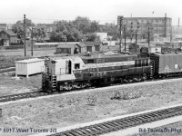 The scene at West Toronto diamond in 1965, looking east off the old Weston Road bridge that once crossed over the tracks here. Note the abundance of section houses by the diamond and the relatively new signal bungalow, which replaced the West Toronto interlocking tower (that was demolished not too long before this photo was taken) when the interlocking here was modernized. The CP Galt Sub curves under the bridge in the foreground, part of the diamonds for the North Toronto and CN Brampton (Weston) Subs are visible behind the signal bungalow, and the MacTier Sub curves north in the background from Osler Ave. <br><br> But probably the most notable thing in this photo: a Canadian Pacific Transfer run heads west to CP's Lambton and West Toronto Yards with CP 8917 in charge, a rare H24-66 "Trainmaster". Built in the 50's by Canadian licensee Canadian Locomotive Company in Kingston using Fairbanks Morse designs and opposed-piston engine technology, the Trainmasters were the most powerful units of their time, turning out 2400 horsepower from a 12-cyliner opposed-piston engine (24 pistons in 12 cylinders!). CP ordered a total of 21 and for a time employed them all over the system, with a 1965 Eastern Region diesel assignment sheet showing 8917 and 8918 assigned Toronto to handle transfer runs between Lambton/West Toronto, Parkdale and Agincourt Yards, often running solo due to their high horsepower. They were also used on mainline freights in the region with other manufacturer's units. <br><br> Ultimately FM/CLC stopped making locomotives in the late 50's, and CP eventually shied away from the more maintenance-intensive CLC engine design. A group of Trainmasters were retired in the late 60's and sold to a supply dealer for engine salvage and scrapping, with the rest of the small fleet dwindling over time until the last three were retired in 1976. 8917 here was retired in April of 1972, and cut up for scrap at CP's Angus Shops in Montreal QC during early 1973.