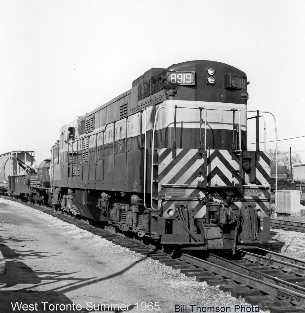 Running long hood forward, CP "Trainmaster" 8919 rolls south on the Galt Sub by West Toronto Station on a transfer run to Parkdale Yard. One of 21 FM/CLC H24-66 units built for the Canadian Pacific Railway in the 50's (8900-8920), they were the most powerful units of their time, and often used solo on transfer assignments in the Toronto area when this photo was taken. Those duties would later fall to the lone MLW RSD17: 8921 "The Empress of Agincourt". Also note the sideways-blocked load in the trailing gondola.