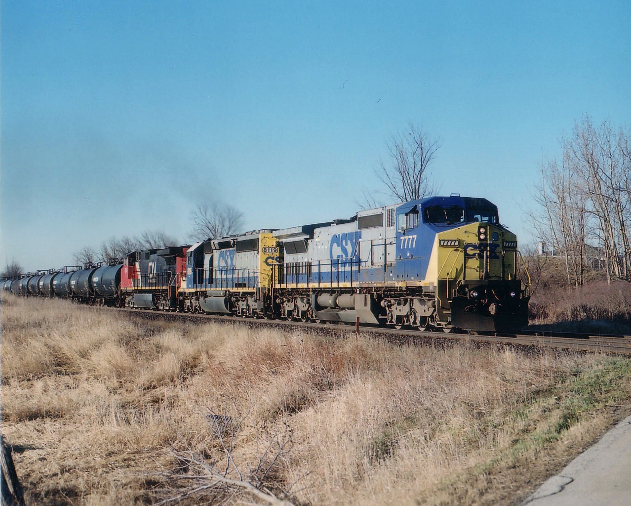This was an interesting and unexpected catch. After just retiring from work, I still had that "urge" to get up in the morning and go somewhere. It wasn't work any more, so it had to be to the tracks. (One can't just quit the daily routine, one has to 'wind down') The night before I had heard CSX 7777 around Paris, just after midnight. There was NO WAY I could ever expect this neat leader to still be in the vicinity when I arrived at Tansley in the morning, but here it is! Don't know what they had been up to all night, but the female conductor sure was in a crabby mood! The fridge had failed and her sandwich was shot.  CSX 7777, 8119 and CN 2684 as train #398 are seen just about to hit the crossing Side Road No.1, near Mile 42 Halton in the early daylight; maybe 0630. Foreign power was plentiful for awhile in early 2007.