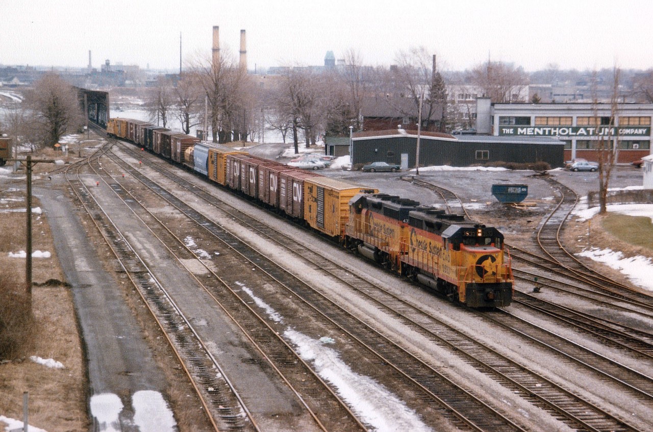From the Central Av bridge looking east toward the Niagara River and the USA, we see a transfer arriving for exchange at the CN Fort Erie yard, which is just off to the other side of this bridge. C&O 3533 and B&O 4350 pull about 20 cars, inc caboose, on this typical dull March morning. Of interest is the old Mentholatum Company building; manufacturers of non-prescription health products. This business had been there for many years, and just this past few months the name has been removed and only memories remain. The business had closed down a while back; in 2009 the Boys and Girls Club of F.E. had leased the property, while in the back (the grey structure) the Bridge Authority had leased space while changes were being made at the border crossing. Track leading up to the building removed many years ago; cars for the local aircraft industry were set off there, I recall "Boeing" cars back in the early 70s. Most track has been pulled up, save for 2 mains and track on left. While looking over this photo I was surprised to see my Grand Marquis parked over by the grey building door. I really walked that far back then? Oh, the horror. :o)
