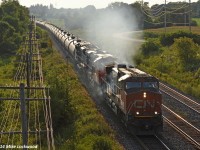 Smoke pours from the engine compartment of IC 2702 as it leads CN 2855 and 8102 and 708's train along a stretch of new triple track just east of Cobourg, Ontario. I'm assuming the diesel doctor was informed of the issue with the leader, but it certainly wasn't impeding their progress... at least not enough to force them to stop. 1852hrs.