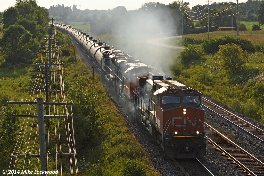 Smoke pours from the engine compartment of IC 2702 as it leads CN 2855 and 8102 and 708's train along a stretch of new triple track just east of Cobourg, Ontario. I'm assuming the diesel doctor was informed of the issue with the leader, but it certainly wasn't impeding their progress... at least not enough to force them to stop. 1852hrs.