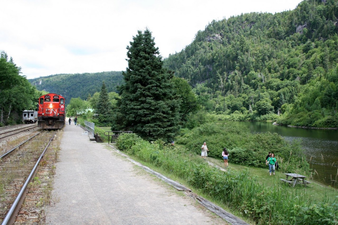 The Agawa Canyon Tour Train, with CN GP9Rm 4110 on the south end, rests at Agawa Canyon Park while the passengers enjoy the scenery at the remote wilderness location of the park. All too soon it's time to head south again.

The small car parked on the house track to the left of the train is the railway's "camp car", which can be rented out for overnight stays, like an RV on rails.