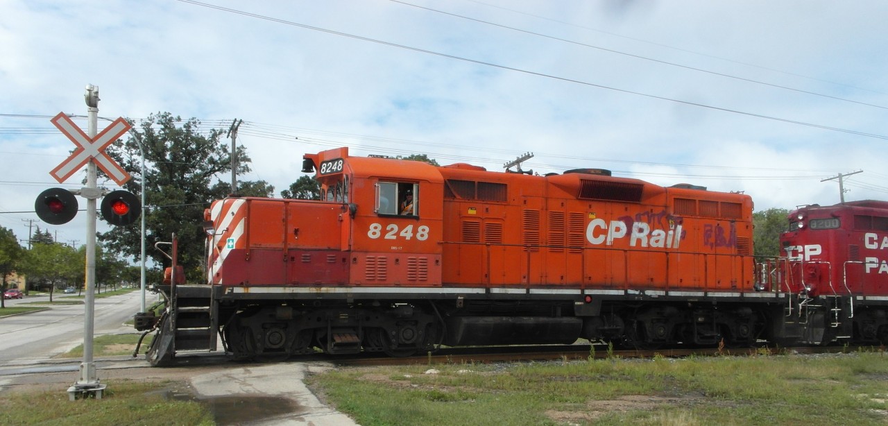 CP 8248 (GP9u) and CP 8200 (GP9u) cross Taylor Ave, with a short train, on the CP La Riviere Sub.