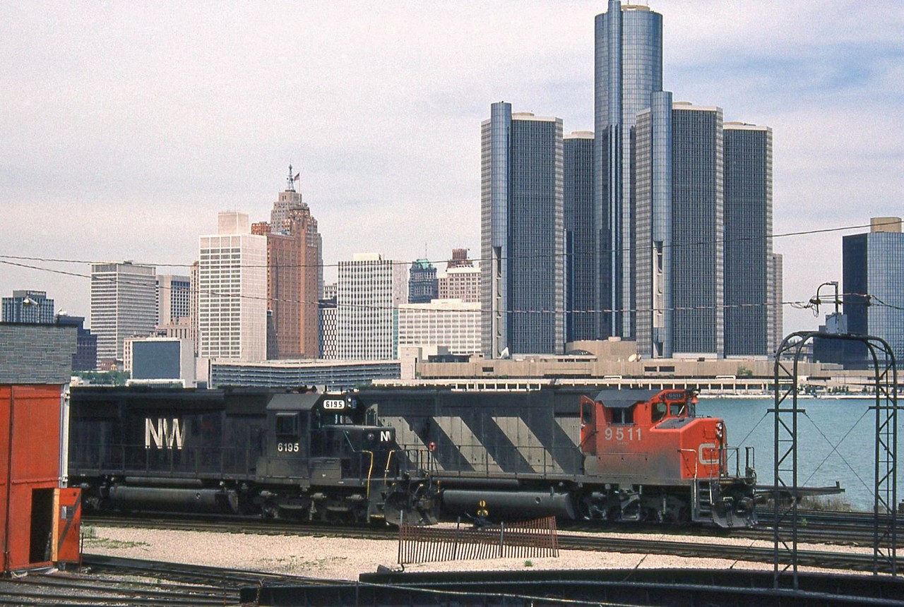 CN GP40-2LW 9511 and N&W SD40-2 6195 rest by the Windsor roundhouse & turntable at CN's old engine terminal, once located along the Detroit River waterfront. Across the border, the skyline of the City of Detroit looms in the background. Today the rails are gone from the Windsor waterfront, along with the roundhouse and turntable. 9511 was retired by CN in the mid-late 90's and now hauls commuter trains for the MBTA. N&W 6195 works for the Norfolk Southern (after the N&W-Southern merger).