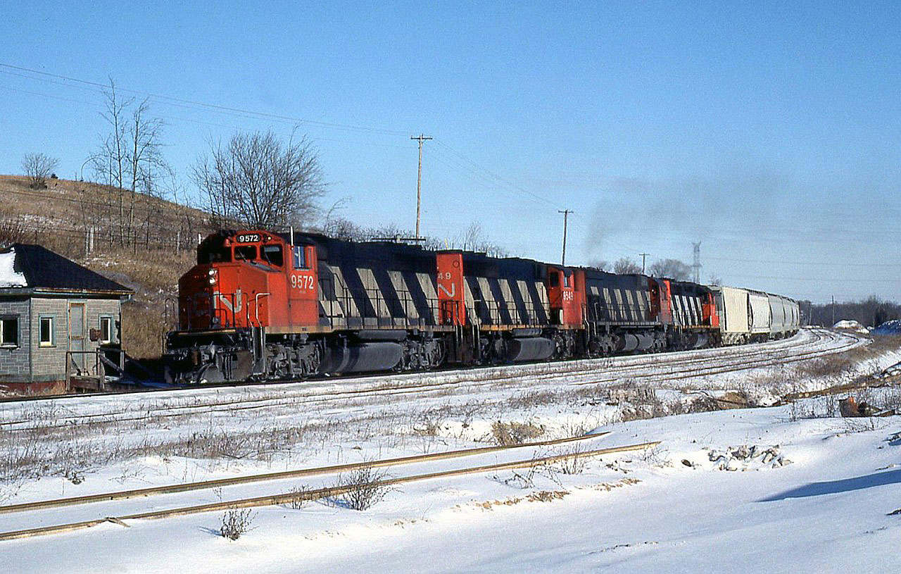 CN train 411 with four units on the head end - GP40-2LW's 9572, 9549, an M636 and another '40 - start the climb up the Niagara Escarpment at Limehouse, on CN's Guelph Subdivision.The train is passing by a quaint sectionhouse(?), which appears to be made or clad in stone. The spur in the foreground is for Acton Limestone Quarries (later Indusmin), who operates a large limestone quarry here and was once an online shipper.  411 was a regular Toronto-Sarnia train that was scheduled on the north route to London and on to Sarnia. It was always an interesting train.