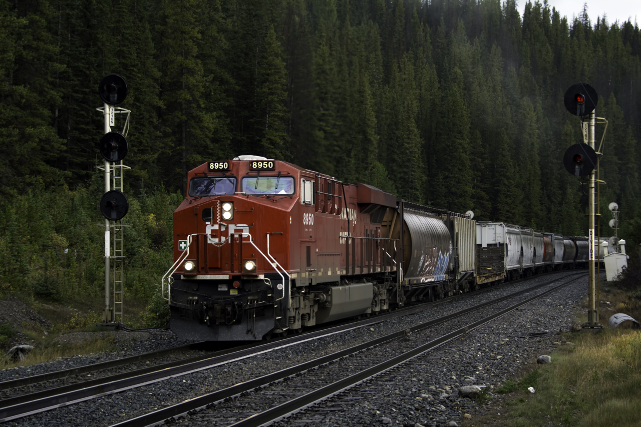 The clouds are low, the sun just beginning break at Divide where CP 8950 is making "walk speed" with a westbound grain.