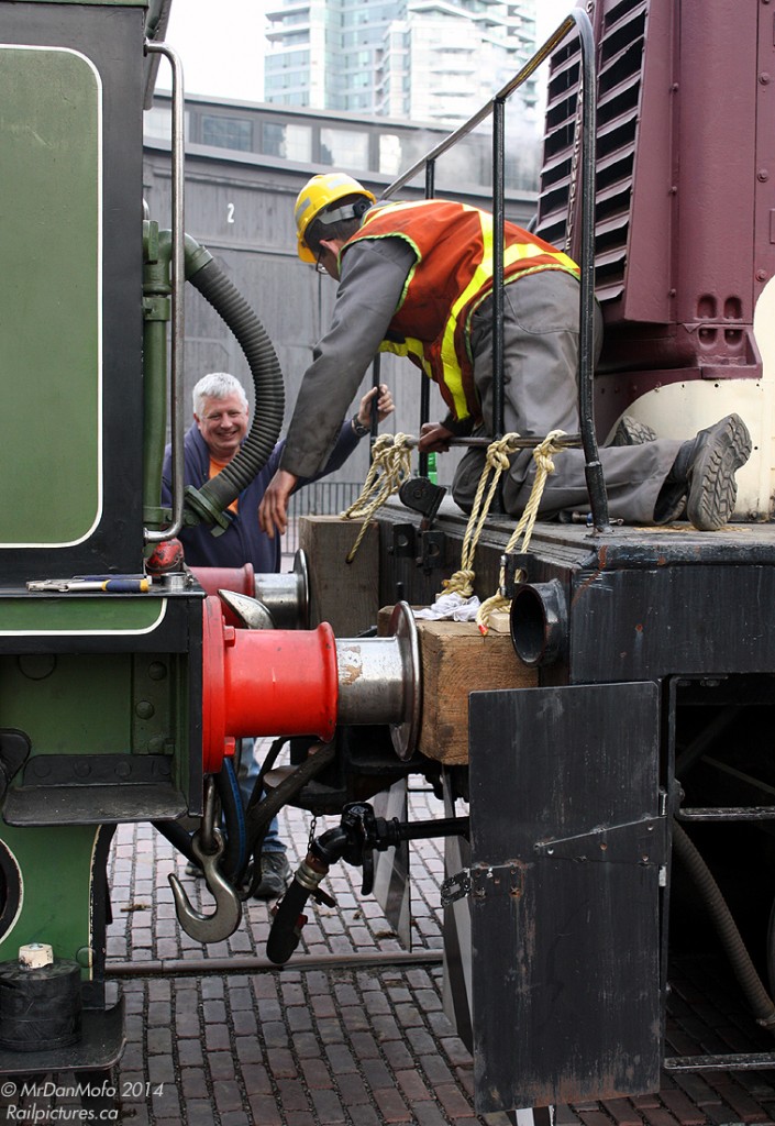 British Steam meets Canadian Handyman-ship  From a North American perspective, the ol' British buffer-and-chain coupling system seems a bit ancient, but it probably gets the job done just as well. Volunteers at the Toronto Railway Historical Association hook up their 50-ton CLC-Whitcomb switcher to "Vicky", a 1893 London & South Western Railway steam engine numbered 563. A museum piece shipped across the Atlantic Ocean, it is shown on loan from the Shildon Locomotion Museum in England for a local production of The Railway Children at Roundhouse Park in Toronto. Used as a switcher (or "shunter" in British terms), the standard North American knuckle coupler and uncoupling levers have been removed off the CLC-W and roped blocks installed to act as buffers for moving Vicky. Once the crew hooks up the coupling link in between, they'll pull the British steamer off of the "tent track", spin it on the turntable, and store it inside the former CPR John Street Roundhouse. A real "Red Green" solution, but when in Canada...