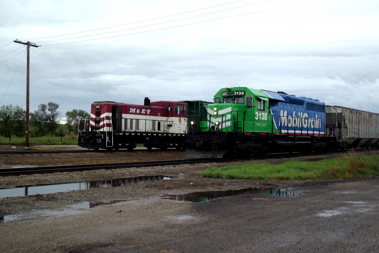 Chamberlain assigned switcher, GE 70 Tonner 604, is returning to the siding after pushing 3 loaded grain hoppers onto the main. MGLX 3138 has connected to the loads and is heading east, towards Regina.