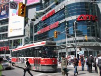Hustle and bustle at Dundas Square: pedestrians, tourists, and students from nearby Ryerson University enjoy a sunny afternoon at Dundas Square. Traffic yields the right-of-way, including a 505 Dundas streetcar on its way east to Broadview Station. All against a backdrop of advertising and store signage that litters the exterior facade of 10 Dundas East (formerly the Metropolis development, at Yonge & Dundas).