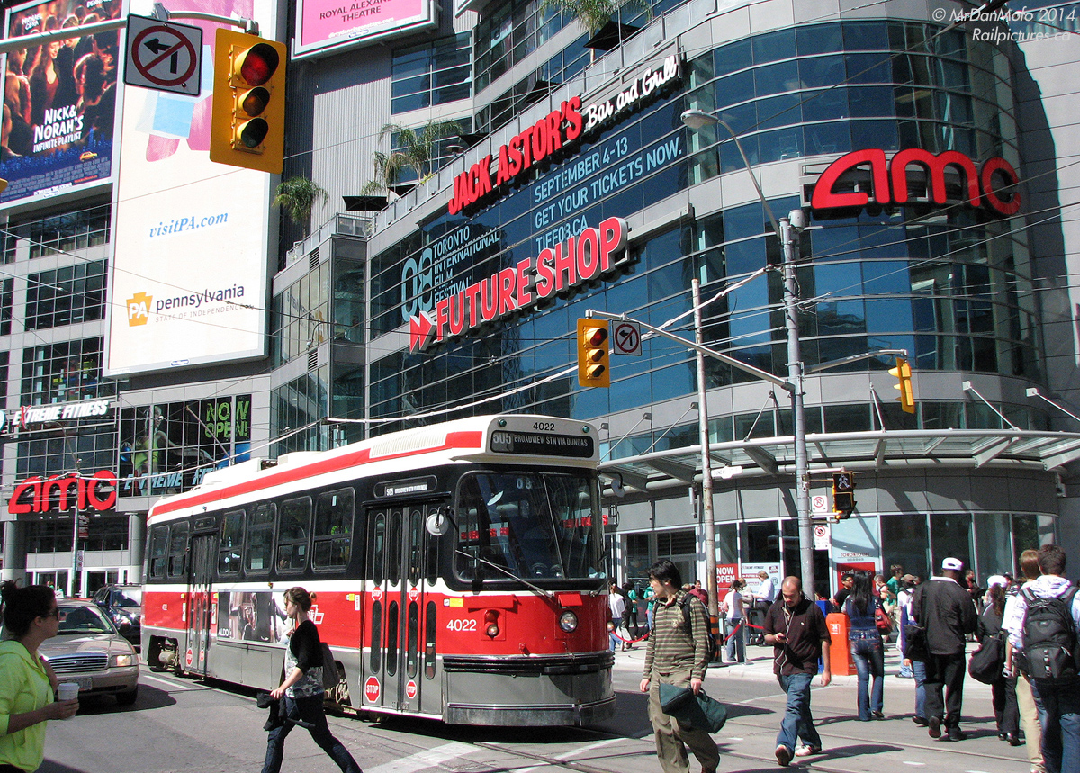 Hustle and bustle at Dundas Square: pedestrians, tourists, and students from nearby Ryerson University enjoy a sunny afternoon at Dundas Square. Traffic yields the right-of-way, including a 505 Dundas streetcar on its way east to Broadview Station. All against a backdrop of advertising and store signage that litters the exterior facade of 10 Dundas East (formerly the Metropolis development, at Yonge & Dundas).