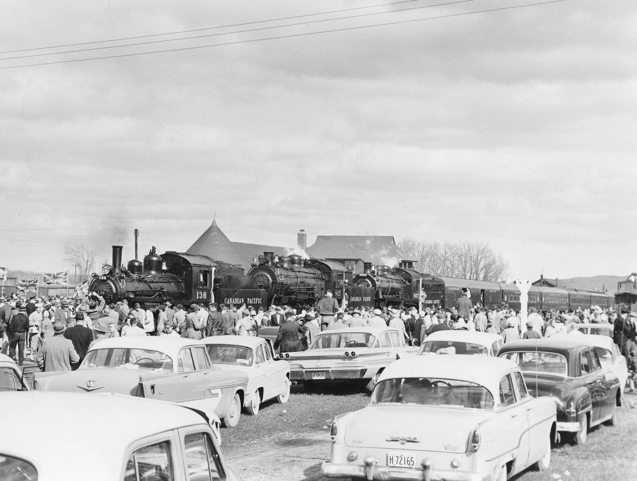 The tripleheader has arrived at Orangeville; quite late but still hundreds were waiting.  A sea of people. Check out those cars! Remember it is 1960. The Chief of Police said there were more people than when the soldiers came home from the War!  Seeing the crowd I immediately cancelled a planned runpast for fear of injuries.  A brass band greeted the passengers and after a brief ceremony the crew set about turning the train for the return trip.  The train was first split to spot the diner at the station (the train arrived one track over) to water it since the hose was not long enough to reach. This delayed remarshalling the train which required moving the baggage car to the other end and the two wooden SUF (Steel Under Frame) coaches to the rear since they could not be marshaled ahead of steel cars.  The CPR had wanted to run the engines and baggage car to turn on the wye at Fraxa (and charge more to do so!).  They said the turntable was out of order. I didn’t believe that so, I went to Orangeville to prove it was still serviceable.  I refused because I did not want to leave people with nothing to look at while this was being done.  I won. My train! The engines were turned, coaled and watered one at a time giving the onlookers a free show.    
Raymond L. Kennedy