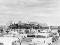 The tripleheader has arrived at Orangeville; quite late but still hundreds were waiting.  A sea of people. Check out those cars! Remember it is 1960. The Chief of Police said there were more people than when the soldiers came home from the War!  Seeing the crowd I immediately cancelled a planned runpast for fear of injuries.  A brass band greeted the passengers and after a brief ceremony the crew set about turning the train for the return trip.  The train was first split to spot the diner at the station (the train arrived one track over) to water it since the hose was not long enough to reach. This delayed remarshalling the train which required moving the baggage car to the other end and the two wooden SUF (Steel Under Frame) coaches to the rear since they could not be marshaled ahead of steel cars.  The CPR had wanted to run the engines and baggage car to turn on the wye at Fraxa (and charge more to do so!).  They said the turntable was out of order. I didn’t believe that so, I went to Orangeville to prove it was still serviceable.  I refused because I did not want to leave people with nothing to look at while this was being done.  I won. My train! The engines were turned, coaled and watered one at a time giving the onlookers a free show.  <br> <br> 
Raymond L. Kennedy 
